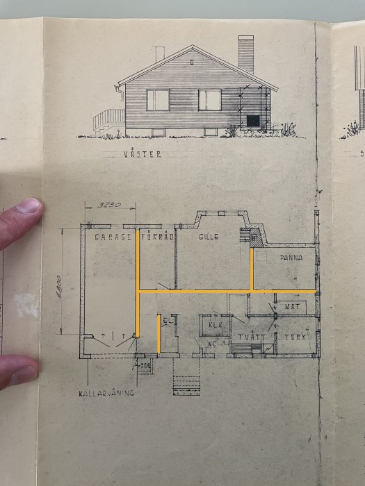 Gammal arkitektritning av enplanshus med källarvåning, hand håller sidan.