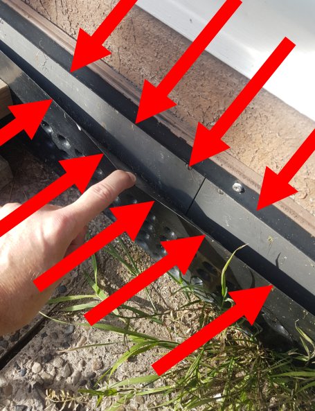 Hand som pekar på skadad byggdetalj med röda pilar som markerar var den har gått sönder.