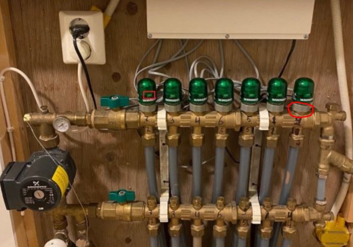 Golvvärmesystem med reglerande ställdon och markerad ring på en rörkoppling.