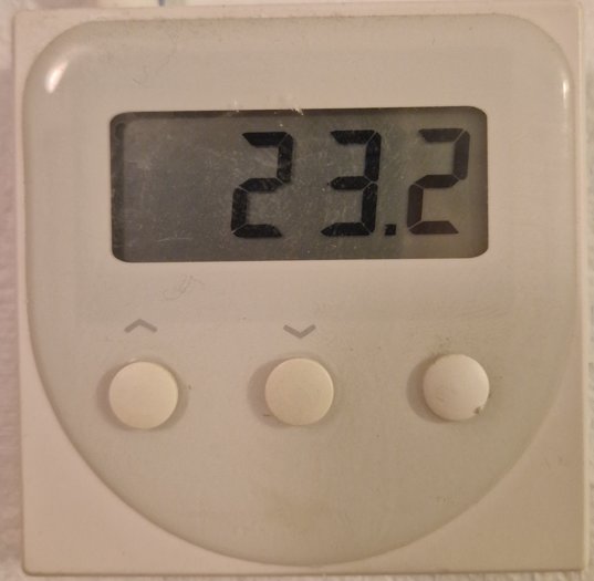 Termostat visar inomhustemperatur 23.2 grader Celsius med tre reglerknappar nedanför.