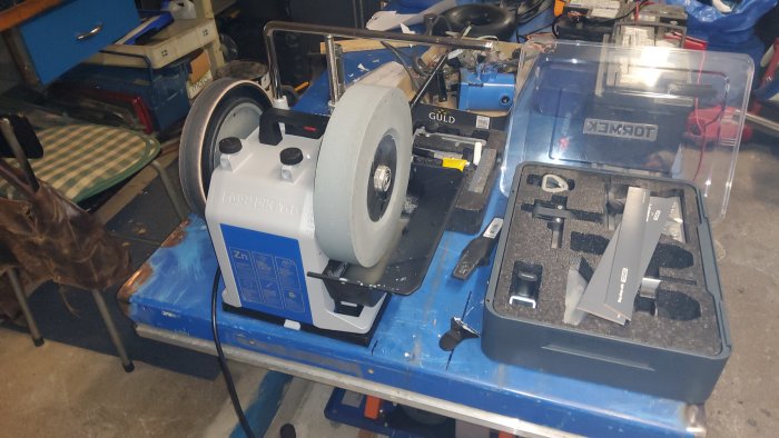 Tormek T8 slipmaskin på arbetsbänk med tillbehör och genomskinligt plastskydd.