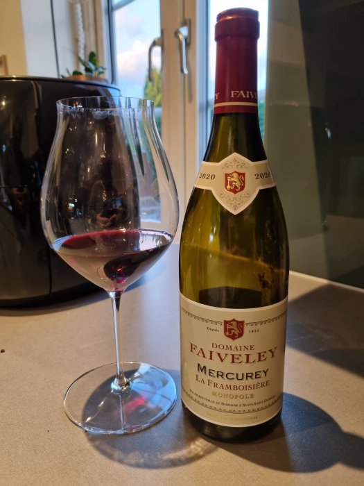 Flaska Pinot Noir från Bourgogne och ett halvfyllt glas vin på ett köksbord.