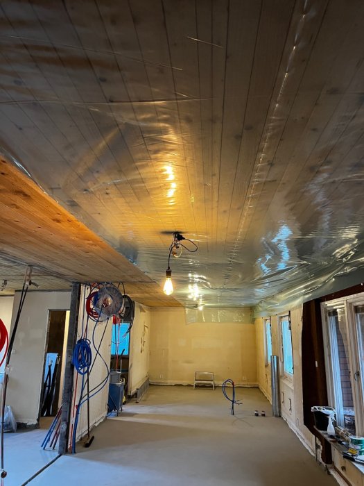 Renoveringsarbete med upphängd plasttäckning i taket av ett utrymme under renovering.