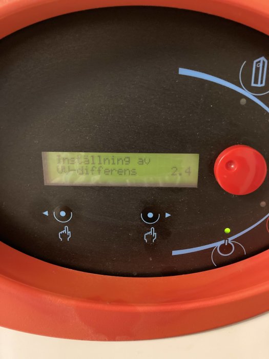 Digital display på en varmvattenberedare visar "Inställning av utilifferens 2,4" med kontrollikoner runtomkring.