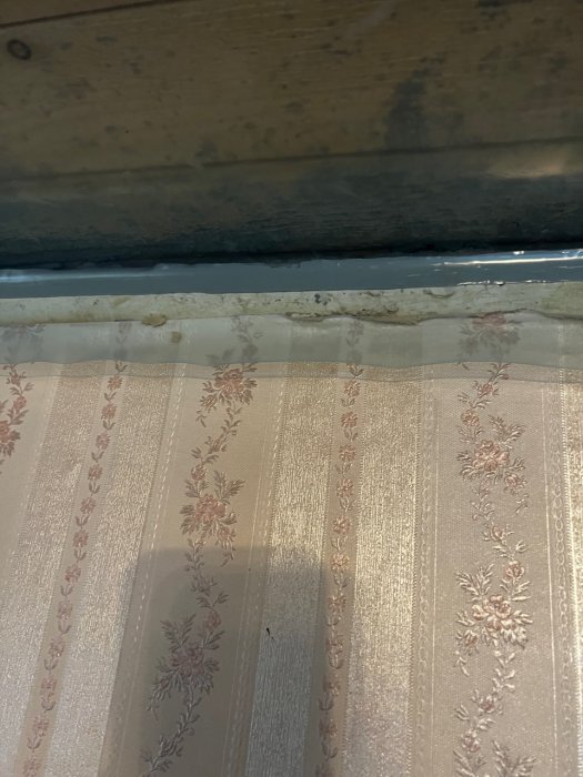 Plastfolie tätad mot en träväggvinkel med synlig butyltejp och överlappande skarvar.