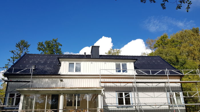 Ett hus med ställningar, förberett för solpanelsinstallation på taket mot en klarblå himmel.