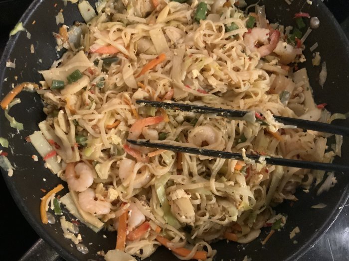 Hemlagad pad thai med räkor och grönsaker i en stekpanna.