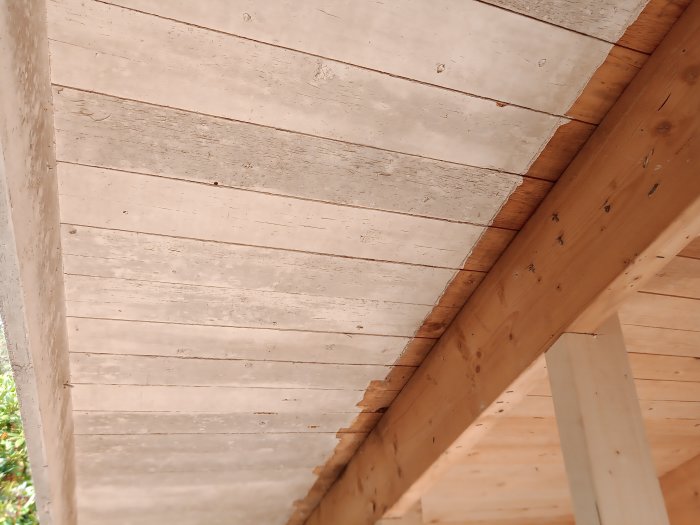 Träkonstruktion av takfot och vindskiva på en byggnad, synliga spikar och trätextur.