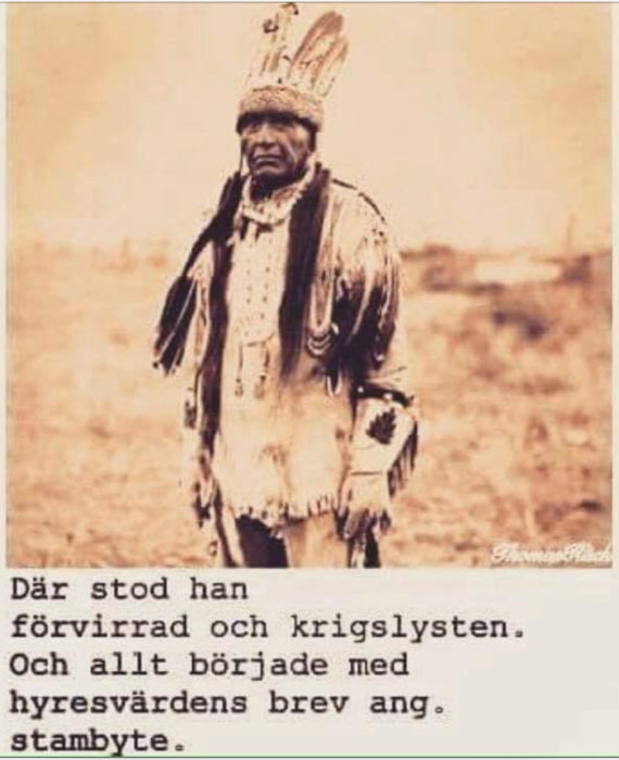 Svartvit bild av en person i traditionell ursprungsbeklädnad med fjäderprydd huvudbonad.