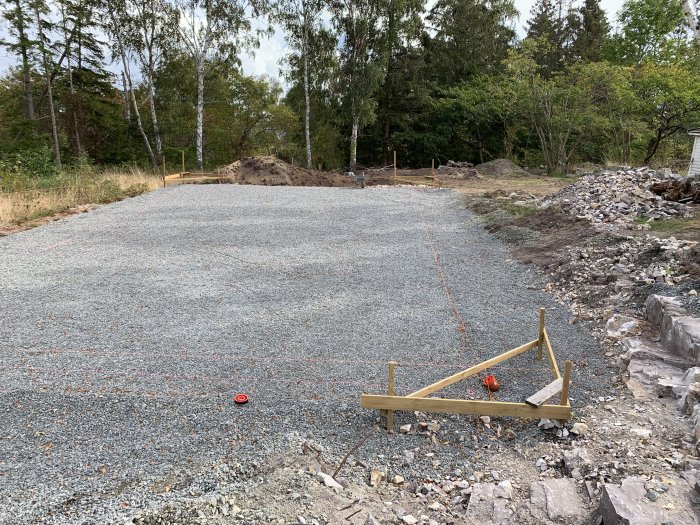 Nygrävd och anlagd dagvattenbrunn på en sandig byggplats omgiven av träd och berg.