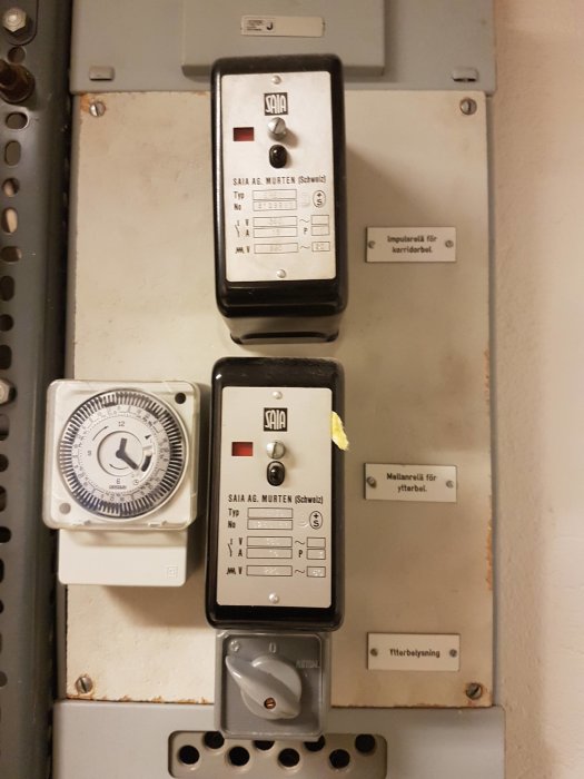 Eldriven tidur och två industrikontakter på en elkretspanel med etiketter.