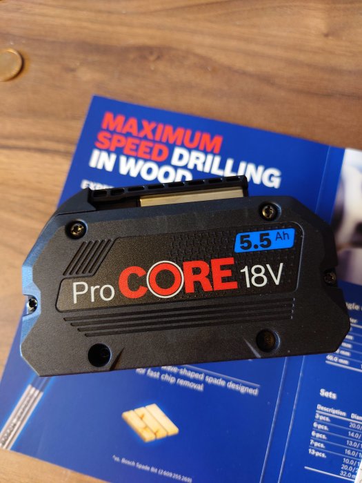 ProCORE 18V 5.5 Ah batteri från ProDeal med AmpShare logotyp, ovanpå en blå broschyr.