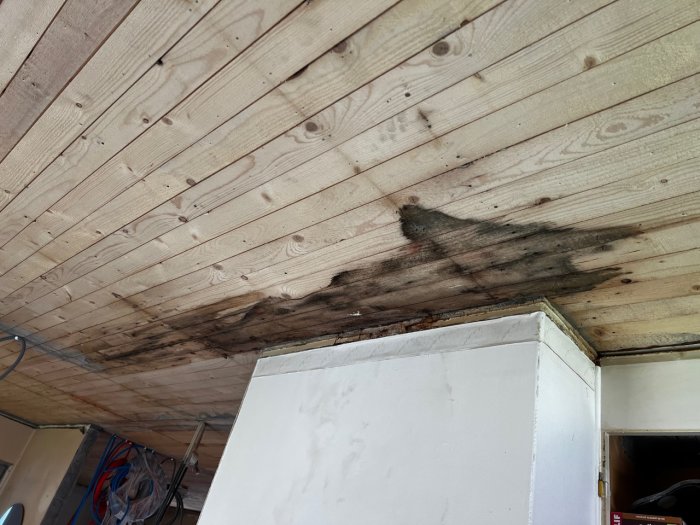 Vattenskadad råspont med mögelpåväxt bredvid en vit skorsten, innan renovering.