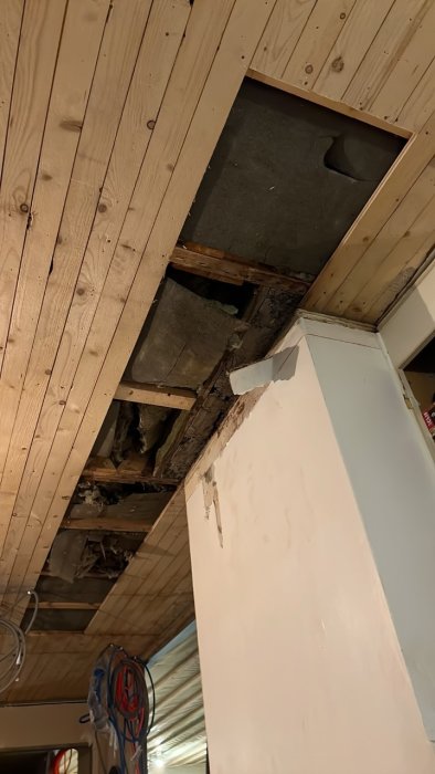 Rivning av skadad råspont och ojämnt putsbruk nära skorstenen i ett byggprojekt.