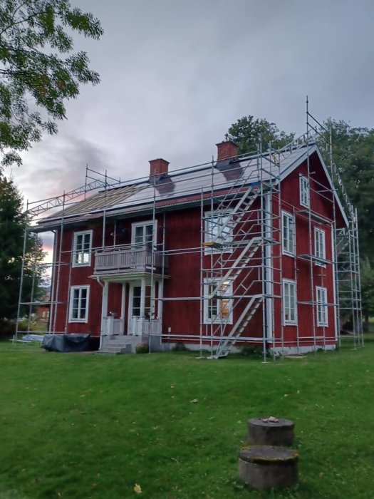 Tvåvåningshus med rött tegel och byggnadsställningar runtom under renovering.