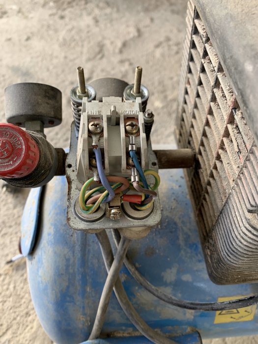 Elmotor och kondensator med ledningar och kontaktpunkter, sannolikt från ett byggprojekt.