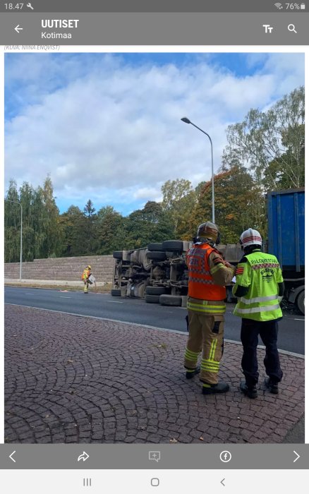 Brandmän på olycksplats där en lastbil vält på en väg nära skog i Helsingfors centrum.