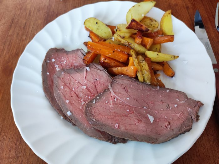 Tallrik med skivor av rostbiff, rostad morot, potatis och sötpotatis, strödd med saltflingor.