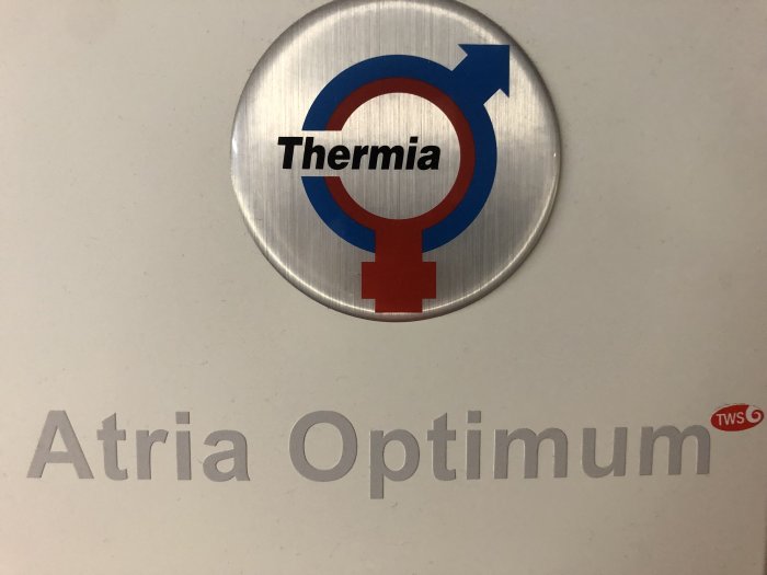 Logotyp för Thermia ovanför texten Atria Optimum på en vit yta av värmepump eller liknande utrustning.