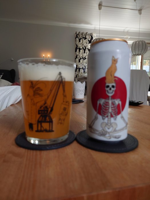 Ett glas öl och en ölburk med unik design på bord i vardagsrum.