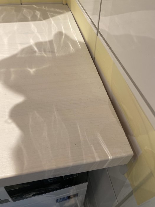 En arbetsbänk med skyddsplast nära en diskmaskin i ett kök under renovering.