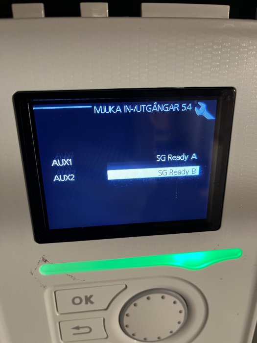 Värmepumpens skärm visar inställningsmenyn för 'SG Ready' med valen 'AUX1: SG Ready A' och 'AUX2: SG Ready B'.