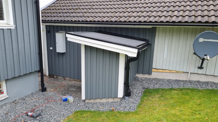 Renoverad södergavel på garage med ny panel och takstänk, redo för hösten.