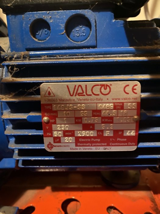 Märkplåt på en elektrisk pump med tekniska specifikationer, märkt VALCO, dammig och monterad på blå och röd maskin.