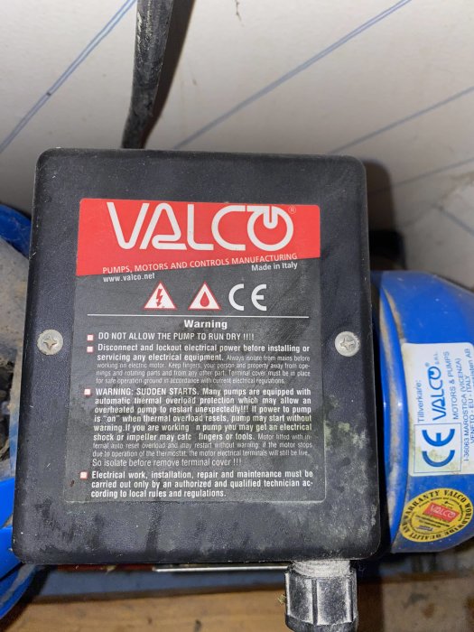 Närbild på en Valco-pump med varningsetiketter och instruktioner.