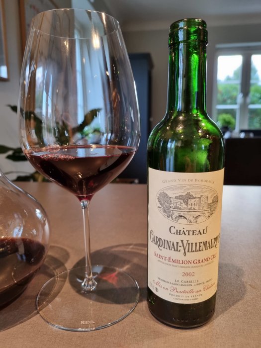 Rödvinsglas med vin bredvid en öppnad halvflaska Saint-Emilion Grand Cru från 2002.