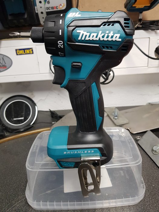 Nytt Makita borrmaskin modell DDF083 utan batteri placerat på ett transparent förvaringslåda på en verktygsbänk.