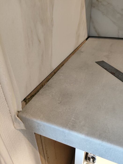 Närbild på spricka mellan marmorbänkskiva och vägg i ett kök.