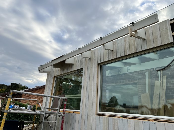 Nyinstallerad hängränna på nyrenoverad byggnadsfasad under mulet himmel.