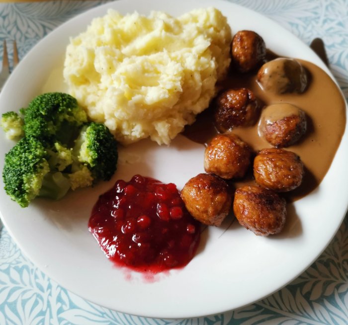 Tallrik med svenska köttbullar, potatismos, brunsås, lingonsylt och kokt broccoli.