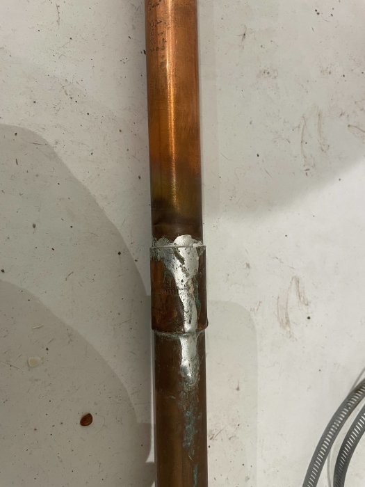 Kopparledning med gammal lödning och nymonterad klämkoppling, utan synlig deformering.