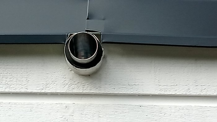 Ventilationsrör som sticker ut från en vit husvägg under en hängränna.