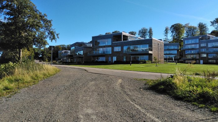 Modernt flerfamiljshus med tegelfasad under klarblå himmel.