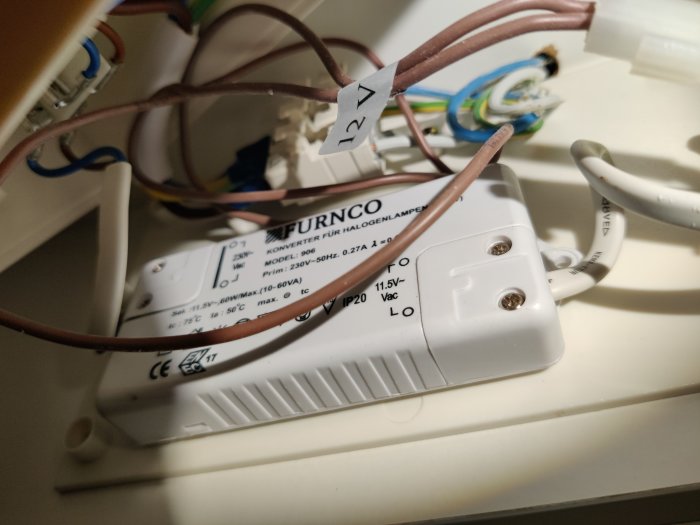 Öppen elektrisk anslutning med transformator för halogenlampor som indikerar problem med blinkande lampor.