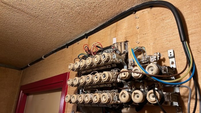 Provisorisk installation av en elcentral med säkringar och öppna ledningar på en vägg under uppbyggnad, med synliga VP-rör.