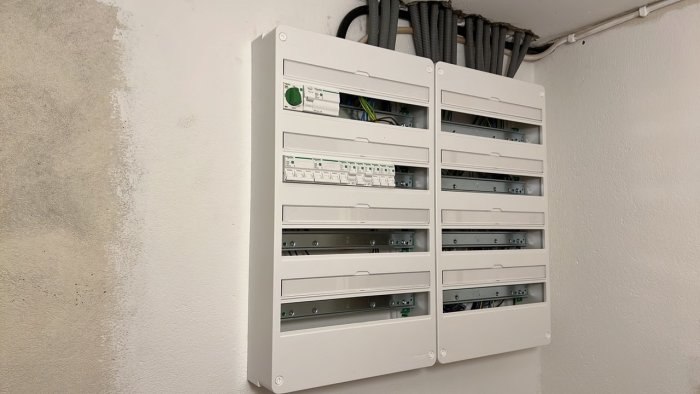 Dubbla elcentraler med 4x18 moduler monterade på vägg med synliga kablar och vp-rör ovanför.