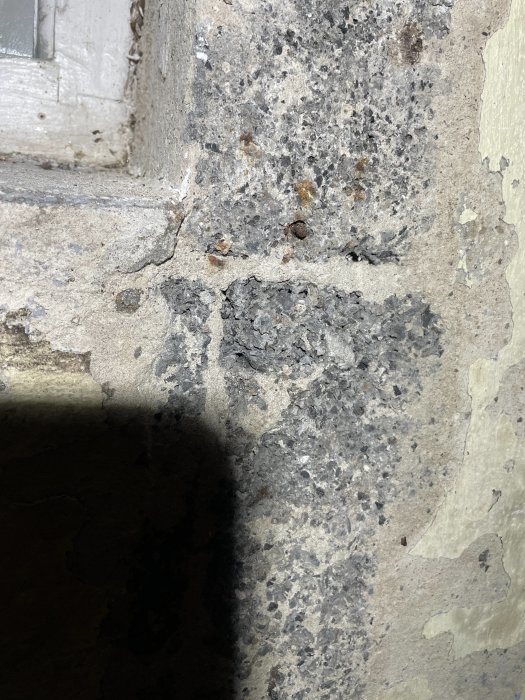 Närbild av slitet betonghörn med sprickbildning och avflagningar.