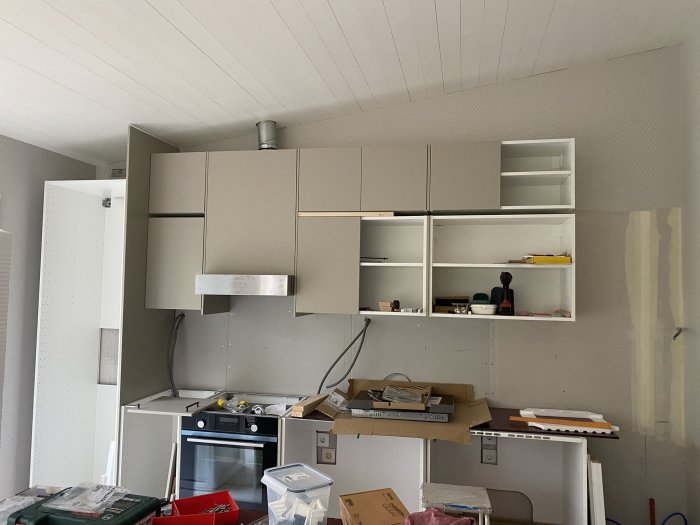 Kök under renovering med överskåp separerade av lister och en öppen hyllsektion.