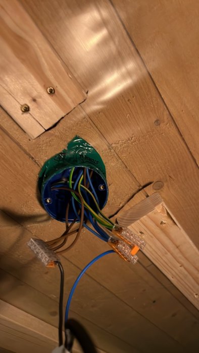 Nyinstallerad takdosa med anslutna elkablar och nätverksslangar i ett tak med synlig stenullsisolering.