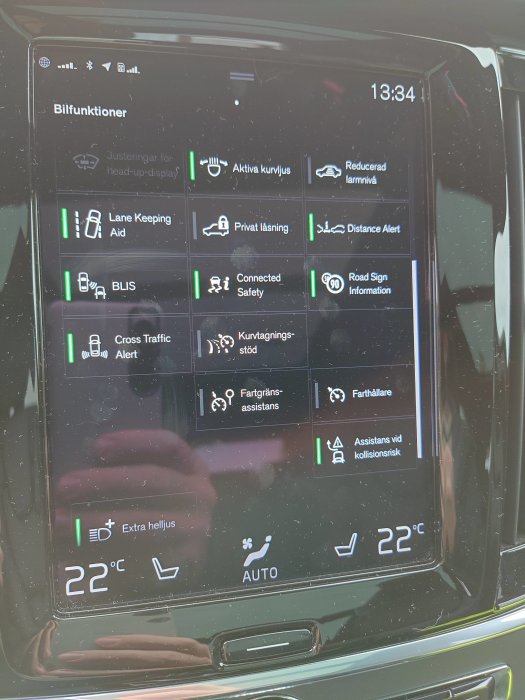 Skärm i bil visar olika aktiviteter för säkerhet och komfort, inklusive temperatur och klockslag.
