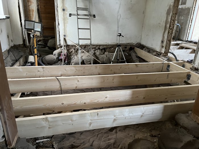 Nybyggda träbjälklag i en renoveringsfas av ett rum med synliga arbetsskeden och byggnadsmaterial.