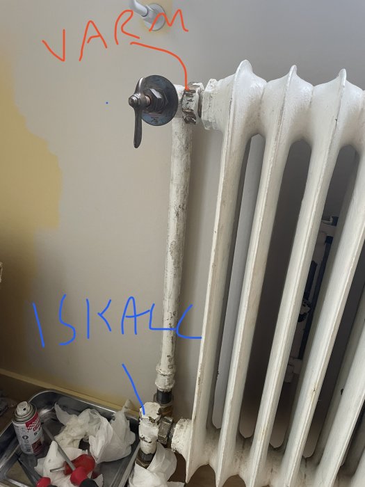 Gammal radiator med markerat varmt och kallt, ventilkran och underhållsmaterial på golvet.