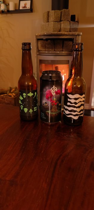 Trebådor med unika etiketter mot en bakgrund av en brasa och en fotografi.