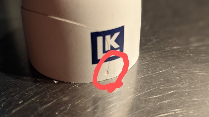 Spricka runt en fördjupning i vit plasthuv markerad med rött.