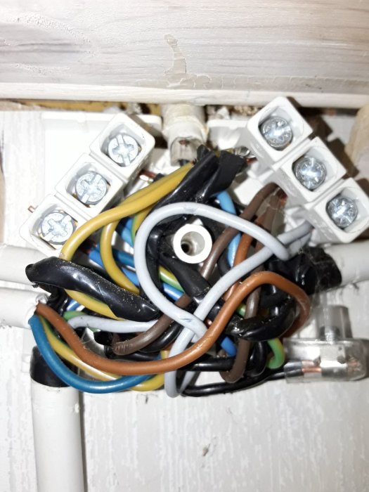 Kopplingsdosa med många elektriska kablar och klemmor, vissa lindade med eltejp.