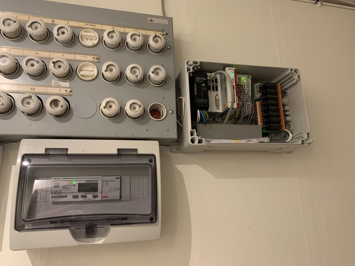 Elektrisk säkerhetspanel bredvid en öppen låda med PLC (Programmable Logic Controller) och kopplingsutrustning